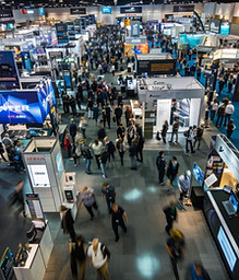 A busy trade show floor full of branded exhibitor booths